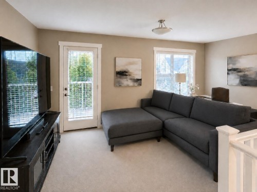 Carpeted living space with a white baluster railing and a glass paneled door - 2337 Frezenberg Avenue Nw, Edmonton, AB - Indoor Photo Showing Living Room