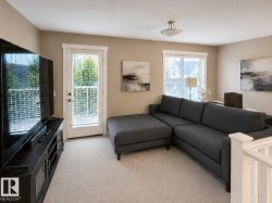 Carpeted living space with a white baluster railing and a glass paneled door - 