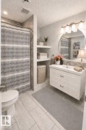 Floating vanity with integrated sink, modern circular mirror, and brushed nickel light fixture - 