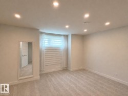Recessed lighting illuminates a neutral-toned room with plush carpet flooring - 