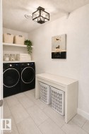 Dedicated laundry area featuring a flush-mount ceiling light, white upper shelving, and light wood-finish flooring - 