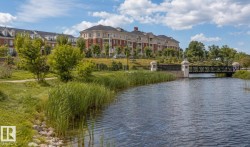 Waterside community featuring a multi-story building with brick and light-toned siding, dormer windows, balconies, and a complementary architectural style - 
