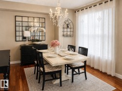 Dining area featuring wood-finish flooring, a chandelier, and a large window with white blinds - 