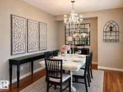 Dining area featuring wood-finish flooring, a white rectangular dining table, and a crystal chandelier - 