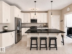 Kitchen featuring a large central island with a dark countertop, white cabinetry, stainless steel appliances, and tile flooring - 