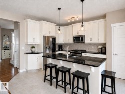 Kitchen featuring white cabinetry, dark stone countertops, and stainless steel appliances - 