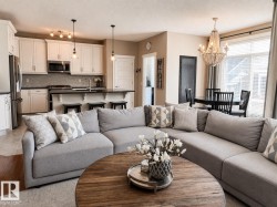 Open-concept living space featuring a kitchen with white cabinetry and stainless steel appliances - 