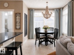 Bright dining area featuring a beaded chandelier, large windows with blinds, and tiled flooring - 