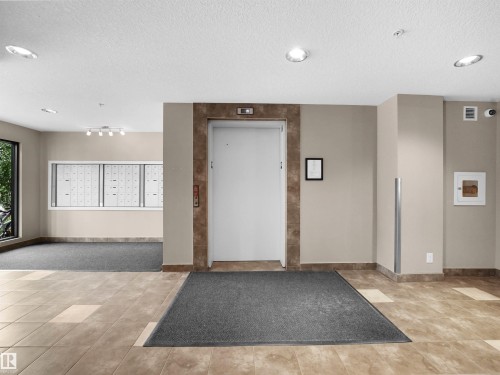 Building entryway featuring a tiled floor, recessed lighting, and an elevator with a stone-look surround - #422 5515 7 Av Sw, Edmonton, AB - Indoor Photo Showing Other Room