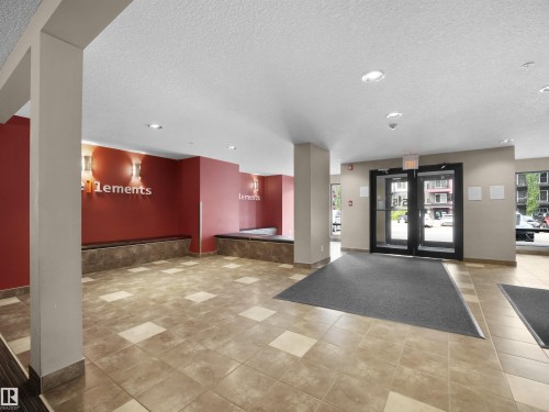 Spacious lobby with checkerboard tile flooring, built-in benches, and red accent walls - #422 5515 7 Av Sw, Edmonton, AB - Indoor Photo Showing Other Room