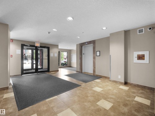 Building lobby featuring glass entry doors, a passenger elevator, recessed lighting, and large format tile flooring - #422 5515 7 Av Sw, Edmonton, AB - Indoor Photo Showing Other Room