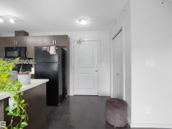 Modern kitchen featuring dark wood-finish cabinetry, a black appliance suite, and a mosaic tile backsplash - 