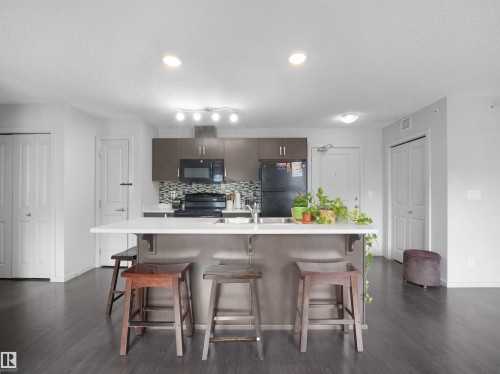 Central kitchen island with a white countertop and integrated sink - #422 5515 7 Av Sw, Edmonton, AB - Indoor Photo Showing Kitchen With Upgraded Kitchen