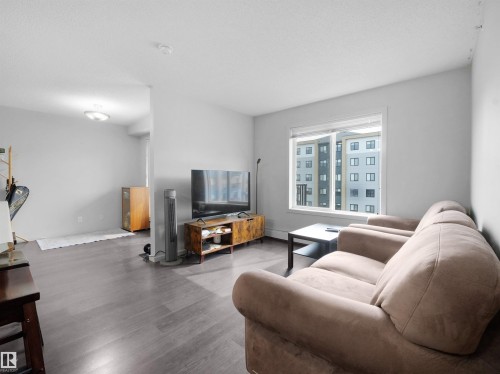 Living area featuring grey wood-finish flooring and a large window - #422 5515 7 Av Sw, Edmonton, AB - Indoor Photo Showing Living Room