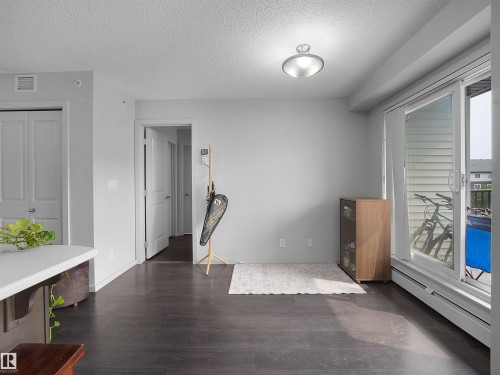 Spacious room featuring dark wood-finish flooring, light grey walls, and a ceiling-mounted light fixture - #422 5515 7 Av Sw, Edmonton, AB - Indoor Photo Showing Other Room