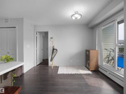 Spacious room featuring dark wood-finish flooring, light grey walls, and a ceiling-mounted light fixture - 