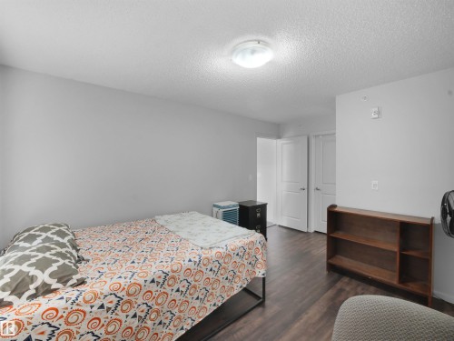 Bedroom featuring wood-finish flooring, light gray walls, a flush-mount ceiling light, and white interior doors - #422 5515 7 Av Sw, Edmonton, AB - Indoor Photo Showing Bedroom