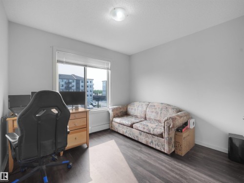 Room featuring dark wood-finish flooring, white walls, and a large window with white blinds - #422 5515 7 Av Sw, Edmonton, AB - Indoor Photo Showing Other Room
