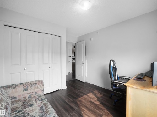 Interior room featuring dark wood-finish flooring, light grey painted walls, and white bi-fold closet doors - #422 5515 7 Av Sw, Edmonton, AB - Indoor