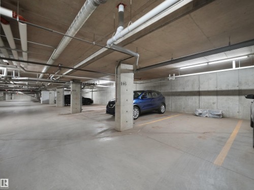 Underground parking garage featuring concrete flooring and exposed ceiling ductwork - #422 5515 7 Av Sw, Edmonton, AB - Indoor Photo Showing Garage