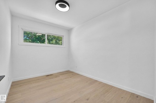Bright room with light wood-finish flooring, white walls, and a modern ceiling light fixture - 6011 93A Avenue Nw, Edmonton, AB - Indoor Photo Showing Other Room