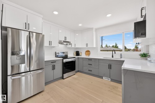 Contemporary kitchen with two-tone cabinetry, stainless steel appliances, and wood-finish flooring - 6011 93A Avenue Nw, Edmonton, AB - Indoor Photo Showing Kitchen With Upgraded Kitchen