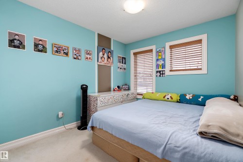 Bedroom featuring two windows with wood blinds, light-colored carpeting, a white ceiling light fixture, and white baseboards - 16748 118 Street Nw, Edmonton, AB - Indoor Photo Showing Bedroom