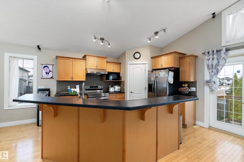 Kitchen featuring wood-finish flooring and a central island with a dark countertop - 16748 118 Street Nw, Edmonton, AB - Indoor Photo Showing Kitchen With Double Sink