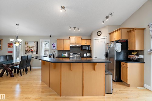 Spacious kitchen featuring wood-finish cabinetry, dark countertops, and stainless steel appliances - 16748 118 Street Nw, Edmonton, AB - Indoor Photo Showing Kitchen