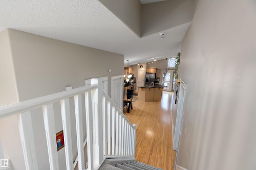 Staircase with light gray carpeting and white banister leading to an open-concept living area - 16748 118 Street Nw, Edmonton, AB - Indoor Photo Showing Other Room