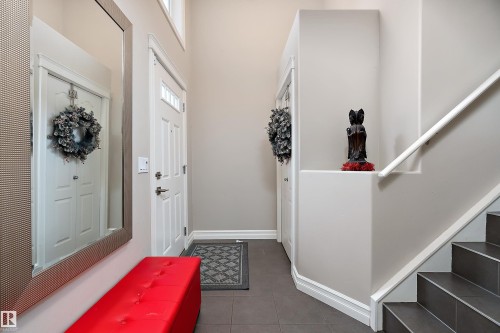 Entryway featuring high ceilings, a full-length wall mirror, white trim, grey tile flooring, and a staircase with white handrail - 16748 118 Street Nw, Edmonton, AB - Indoor Photo Showing Other Room