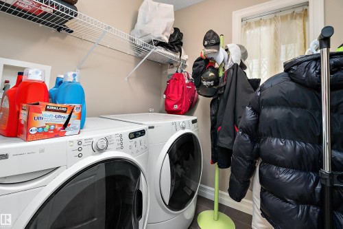 Laundry area featuring front-loading washer and dryer, wire shelving, and a window for natural light - 16748 118 Street Nw, Edmonton, AB - Indoor Photo Showing Laundry Room