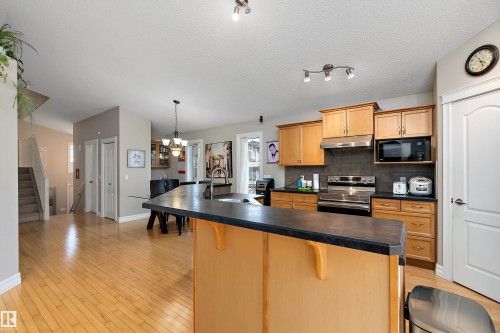Kitchen with light wood-finish cabinetry, stainless steel appliances, dark countertop, and tile backsplash - 16748 118 Street Nw, Edmonton, AB - Indoor Photo Showing Kitchen