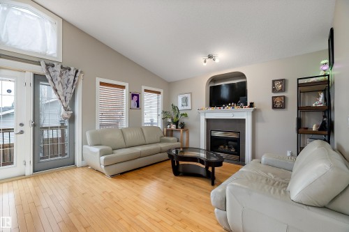 Living area with wood-finish flooring, vaulted ceiling, and dual windows with blinds - 16748 118 Street Nw, Edmonton, AB - Indoor Photo Showing Living Room With Fireplace