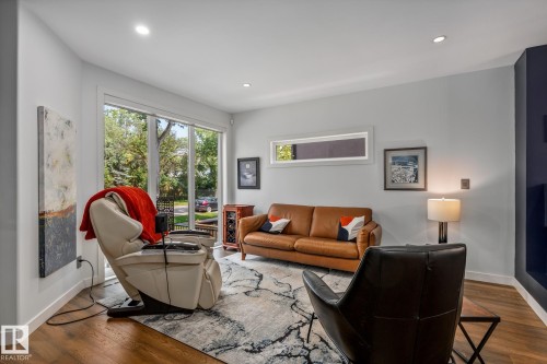 Light-filled interior featuring expansive glass doors, recessed lighting, wood-finish flooring, a contemporary area rug, and a horizontal transom window - 14221 101 Avenue Nw, Edmonton, AB - Indoor Photo Showing Living Room