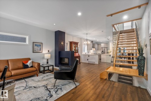 Open-concept living space featuring wood-finish flooring, a modern fireplace with a dark accent wall, and recessed lighting - 14221 101 Avenue Nw, Edmonton, AB - Indoor Photo Showing Living Room