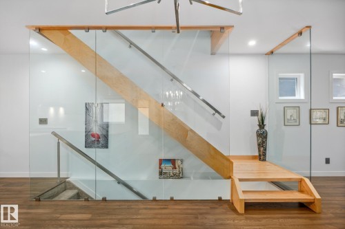Modern staircase featuring glass panel railings, wood-finish treads, and stainless steel handrails - 14221 101 Avenue Nw, Edmonton, AB - Indoor Photo Showing Other Room