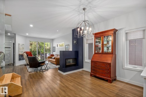 Open-concept interior featuring wood-finish flooring, recessed lighting, and a contemporary chandelier - 14221 101 Avenue Nw, Edmonton, AB - Indoor Photo Showing Living Room With Fireplace