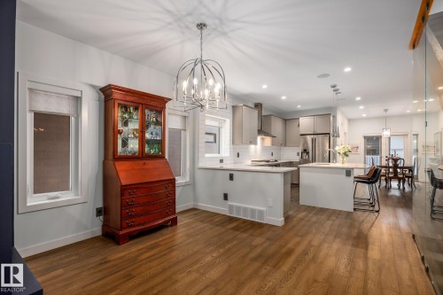 Open-concept living space featuring wood-finish flooring, a modern kitchen with stainless steel appliances, white subway tile backsplash, and light-toned cabinetry - 14221 101 Avenue Nw, Edmonton, AB - Indoor