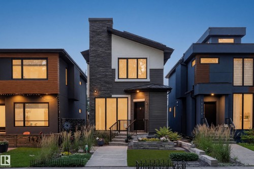 Contemporary facade featuring a stone-clad chimney, dark siding, and contrasting white accents - 14221 101 Avenue Nw, Edmonton, AB - Outdoor