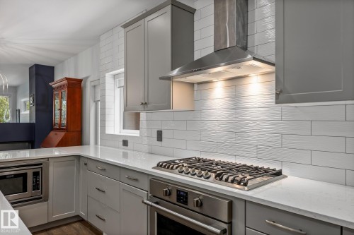 Kitchen featuring light grey cabinetry with brushed nickel hardware, white countertops, and a textured white subway tile backsplash - 14221 101 Avenue Nw, Edmonton, AB - Indoor Photo Showing Kitchen With Upgraded Kitchen