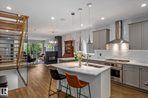 Modern kitchen featuring a central island with integrated double sink, stainless steel appliances, and grey shaker-style cabinetry with subway tile backsplash - 14221 101 Avenue Nw, Edmonton, AB - Indoor Photo Showing Kitchen With Upgraded Kitchen