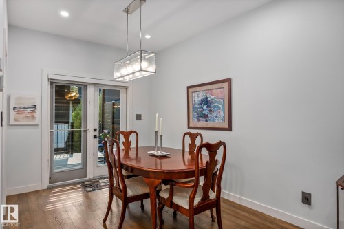 Dining area featuring French doors leading to an outdoor space, wood-finish flooring, recessed lighting, a modern rectangular chandelier, and light-toned wall finishes - 14221 101 Avenue Nw, Edmonton, AB - Indoor Photo Showing Dining Room