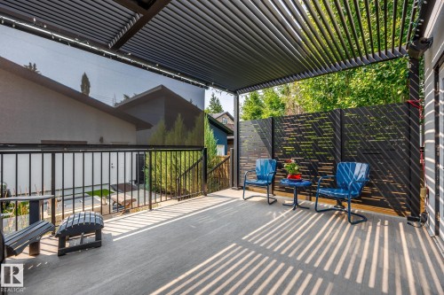 Spacious outdoor deck featuring a louvered pergola for sun control, a retractable privacy screen, contemporary black railing, and a decorative black privacy fence - 14221 101 Avenue Nw, Edmonton, AB - Outdoor With Deck Patio Veranda With Exterior