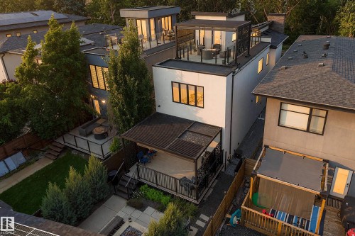 Modern exterior with multiple rooftop terraces featuring glass railings, a covered balcony, and a manicured backyard with a patio - 14221 101 Avenue Nw, Edmonton, AB - Outdoor With Exterior