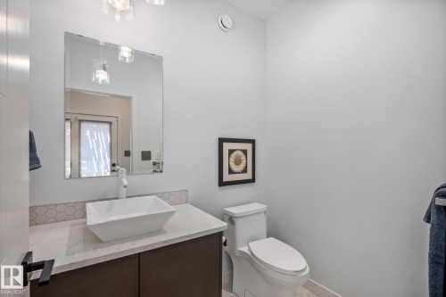 Contemporary vanity featuring a rectangular vessel sink, white faucet, and light-toned countertop with a hexagonal tile backsplash - 14221 101 Avenue Nw, Edmonton, AB - Indoor Photo Showing Bathroom