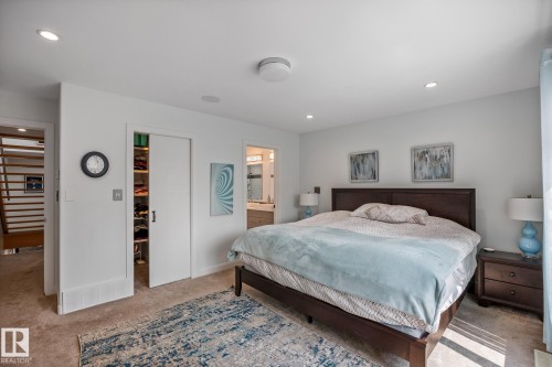 Spacious room featuring neutral carpeting, recessed ceiling lighting, a built-in closet with sliding doors, a ceiling-mounted light fixture, and an entry to an additional space - 14221 101 Avenue Nw, Edmonton, AB - Indoor Photo Showing Bedroom