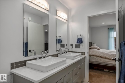 Dual vessel sinks set atop a light countertop with a tiled backsplash - 14221 101 Avenue Nw, Edmonton, AB - Indoor Photo Showing Bathroom