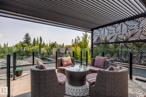 Outdoor patio featuring a louvered pergola roof, patterned privacy screen, and glass railing - 14221 101 Avenue Nw, Edmonton, AB - Outdoor With Deck Patio Veranda