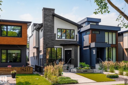 Modern architecture featuring a prominent stone facade, dark-frame windows, a flat roofline, and a well-manicured lawn with stone landscaping elements - 14221 101 Avenue Nw, Edmonton, AB - Outdoor With Facade